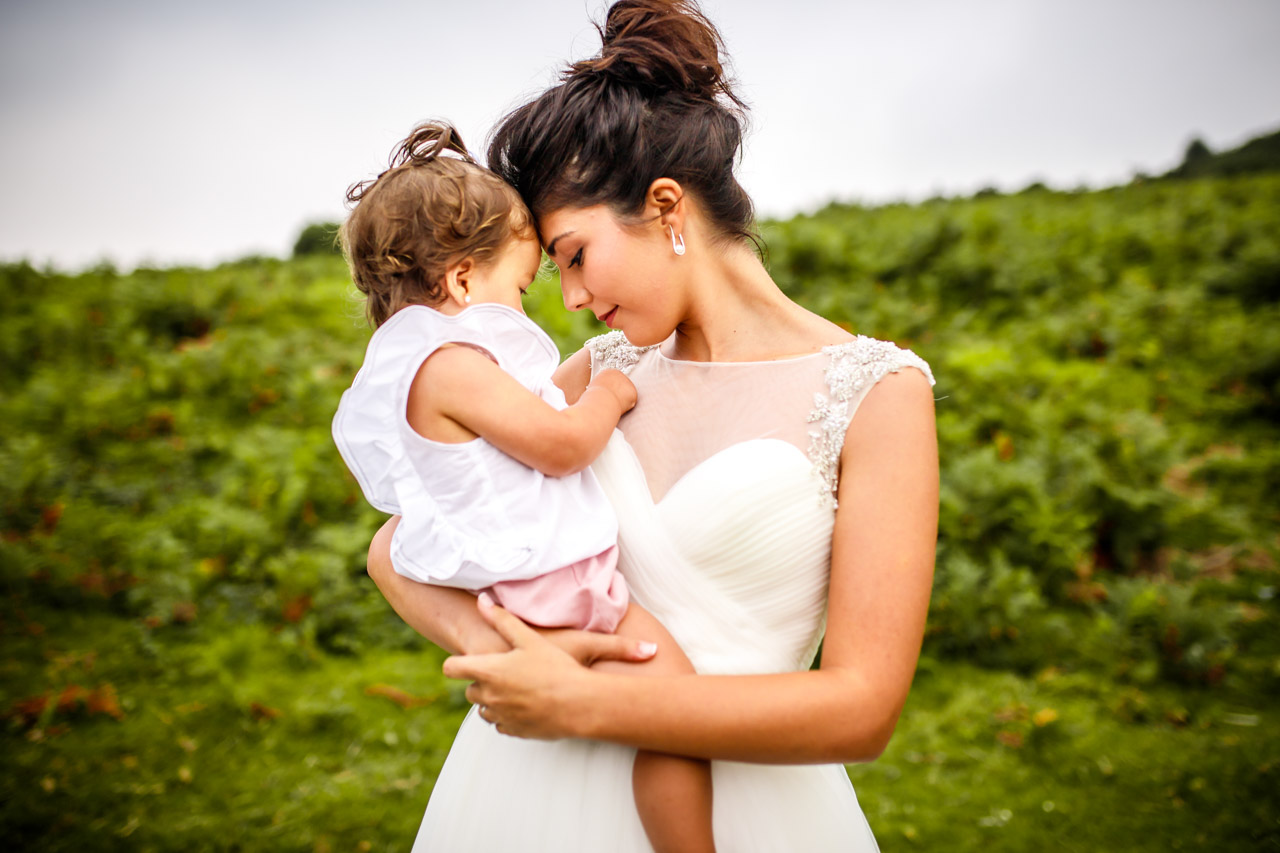 la novia con su hija en brazos en una postboda en peñas de aia