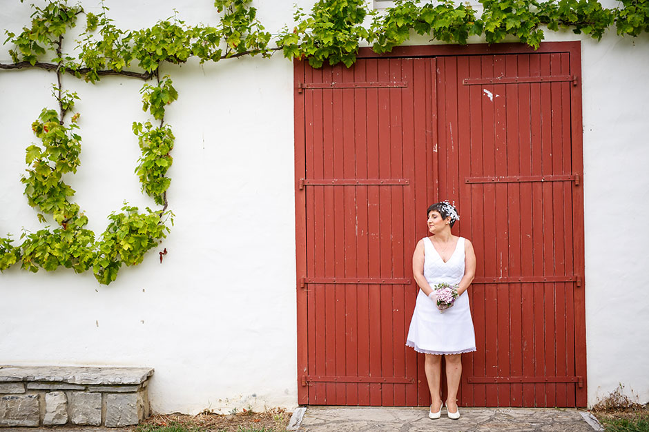 puerta roja y enredadera con la novia en un reportaje de pareja con fotografo de bodas en guipuzcoa
