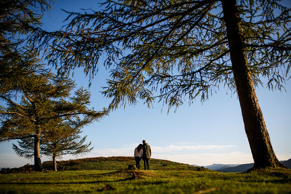 pareja de novios abrazados de espaldas observando el horizonte en el monte