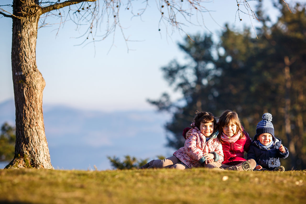 tres niños en el monte en un reportaje de familia sonriendo