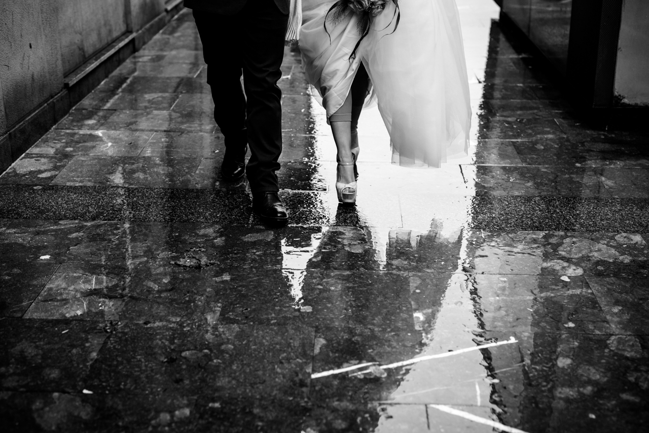 pareja de recien casados andando por las calles de san sebastian mojadas