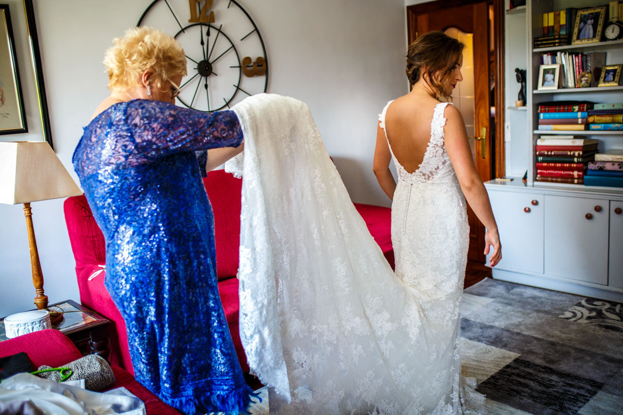 la madre de la novia colocando bien el vestido a la novia en una boda en guadalupe