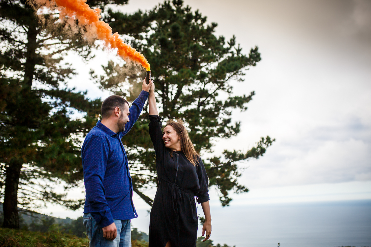 pareja levantando una bomba de humo naranja