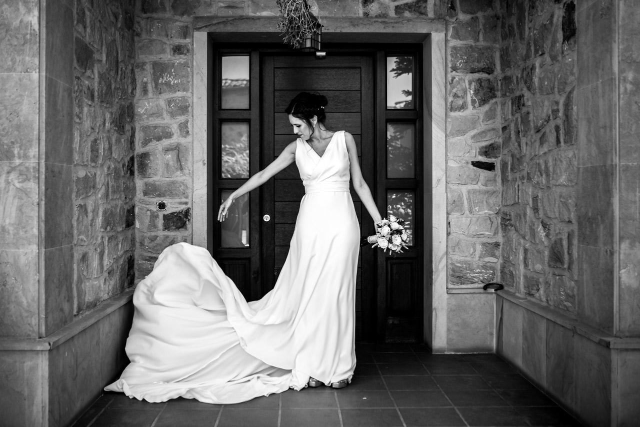 la novia se coloca bien el vestido en la entrada de su casa en una boda en soria